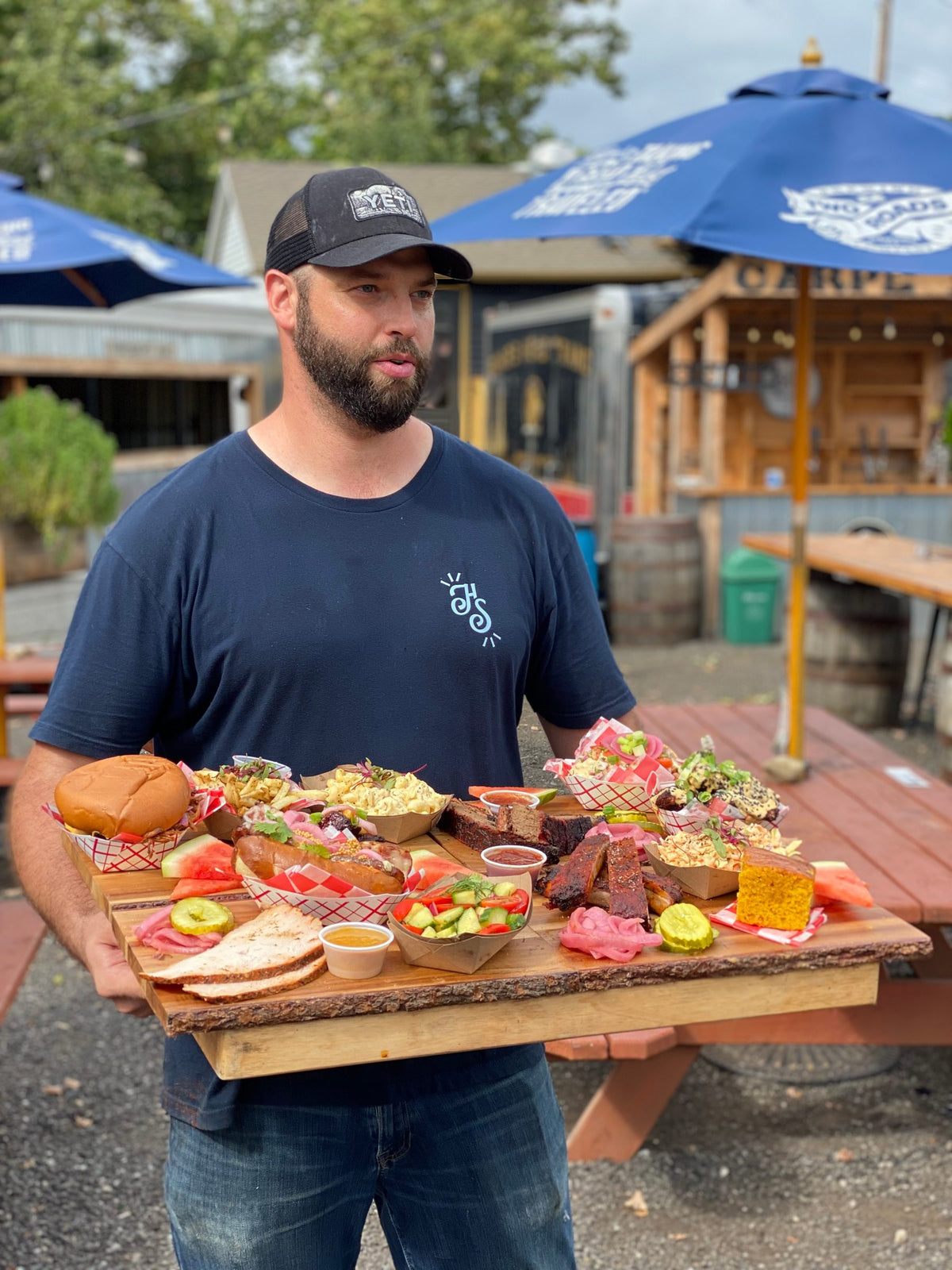 Hindsight pitmaster holding a board of barbecue on the patio