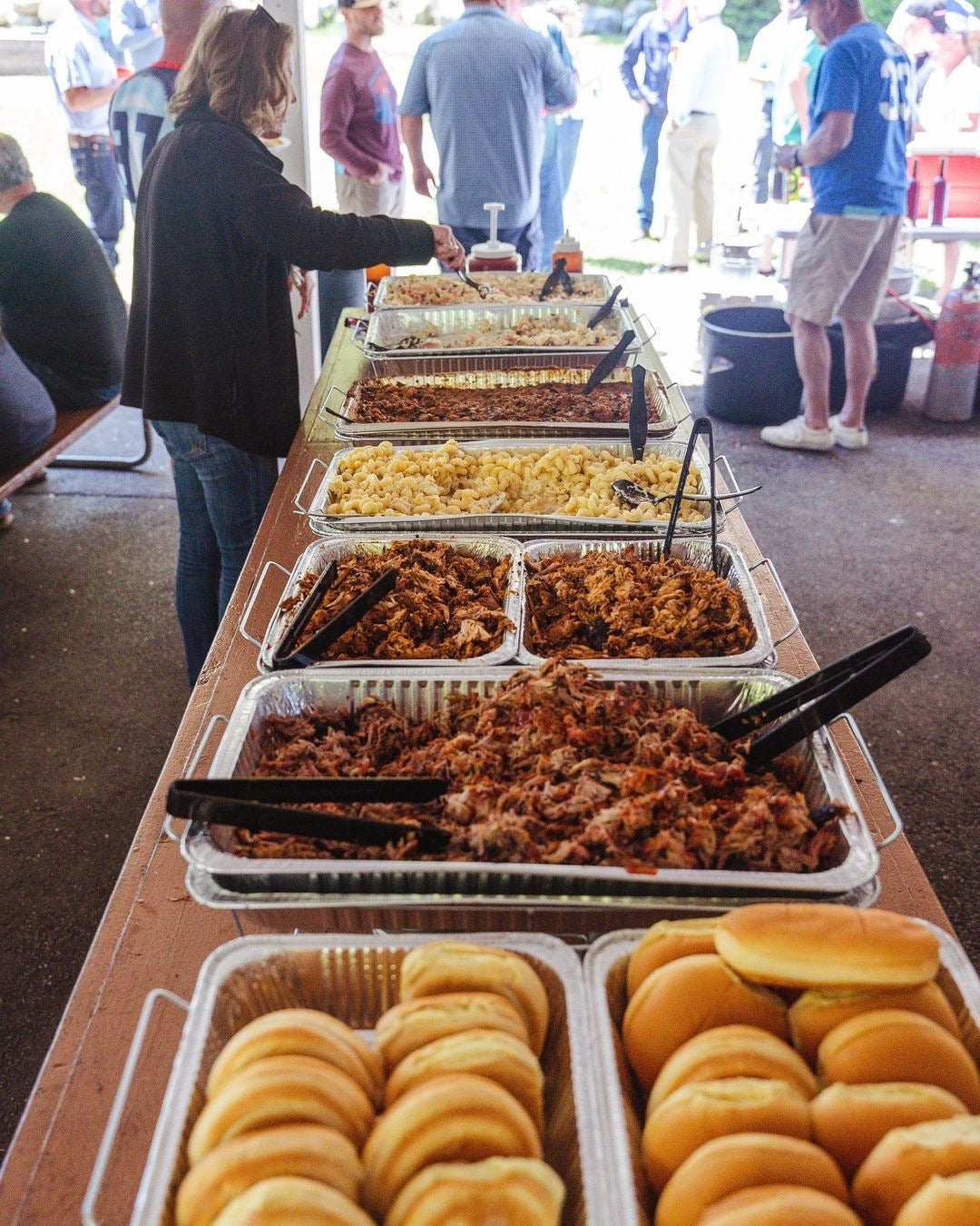 Hindsight BBQ catering buffet: trays of pulled pork, mac and cheese and buns at an outdoor event