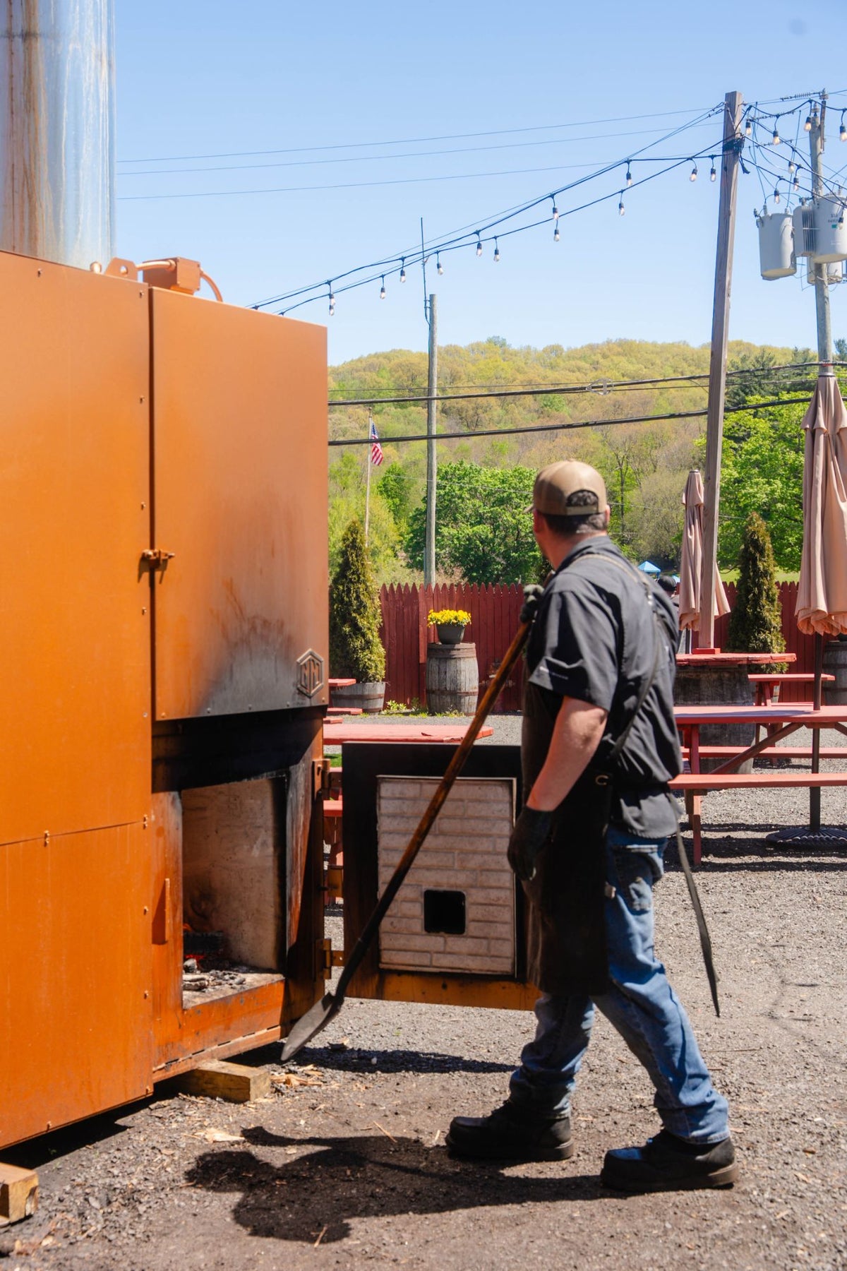Hindsight pitmaster loading the firebox of the wood smoker